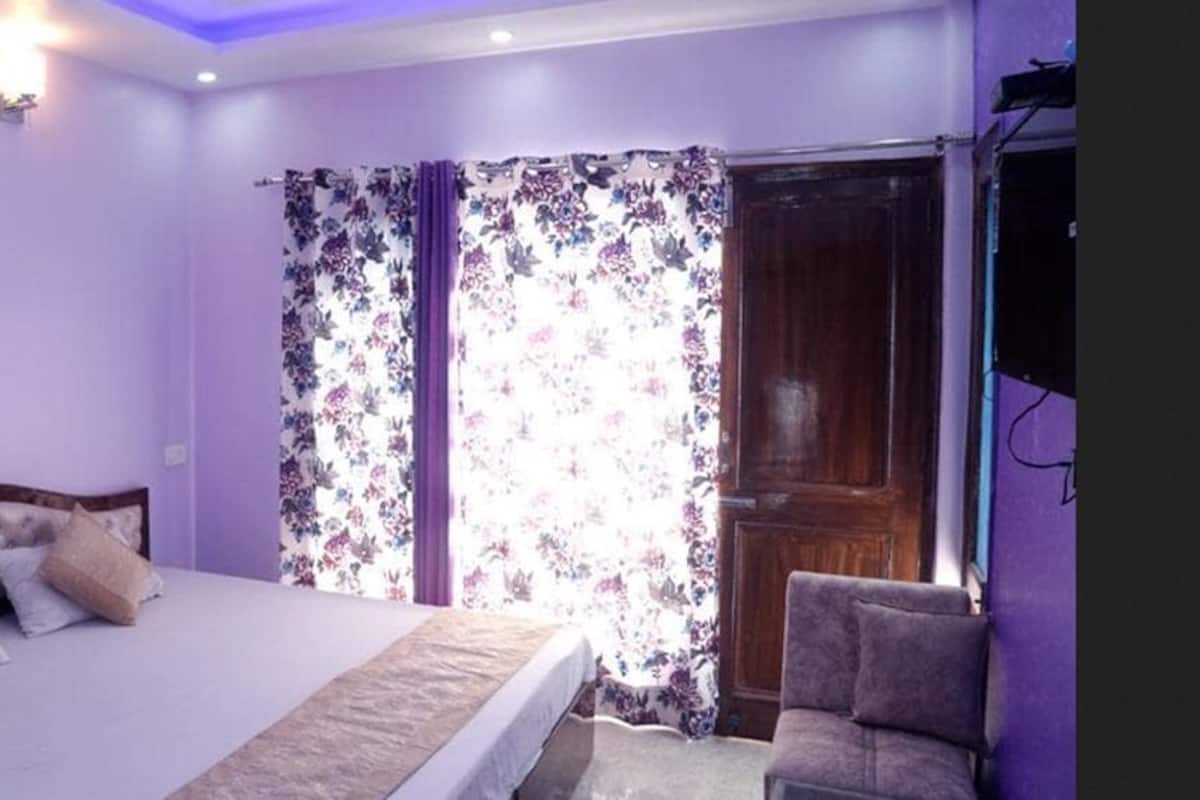 A bedroom with a bed, a chair, and a window with floral curtains.