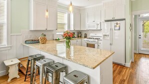 A kitchen with white cabinets, a granite countertop, a stainless steel refrigerator, and a gas stove.