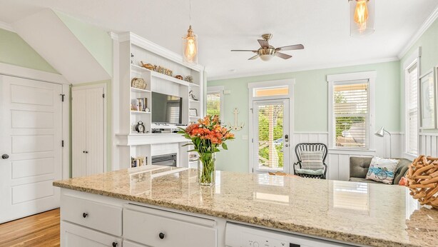 A kitchen with a granite countertop, white cabinetry, a built-in oven, and a dishwasher.
