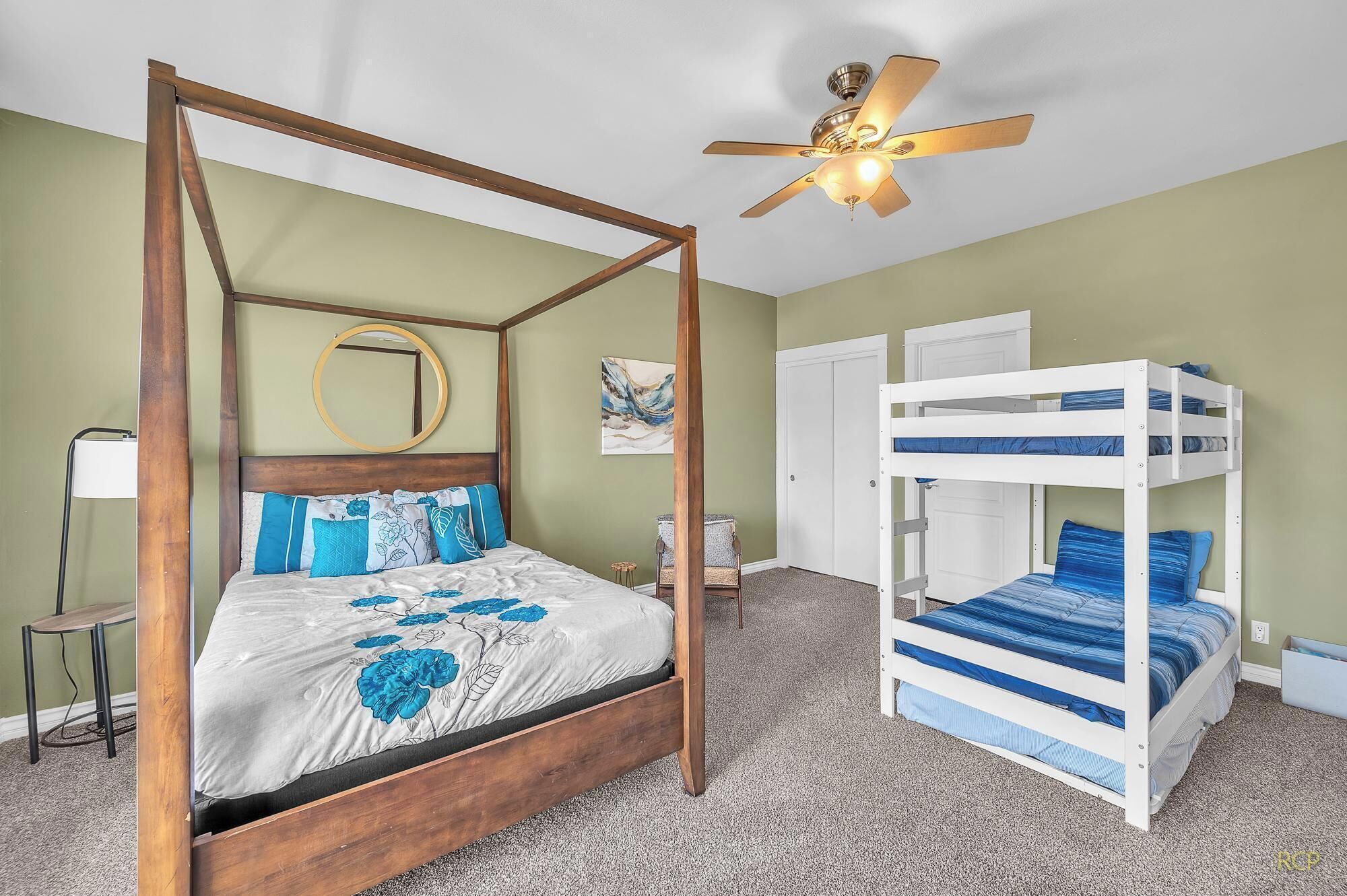 A four-poster bed with a wooden frame, a ceiling fan, and a bunk bed to the right.
