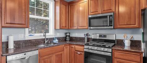 A modern kitchen with wooden cabinets, a Bosch dishwasher, a stainless steel stove, and a microwave.