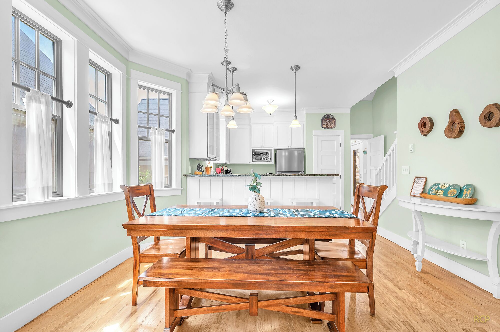 A spacious kitchen with white cabinets, a stainless steel refrigerator, and a dining area with a wooden table and chairs.