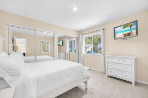 Un dormitorio con dos camas, televisión, cómoda y vista a la playa.