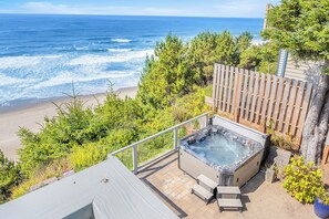 Un jacuzzi con vista al océano, rodeado de vegetación y una valla de madera.