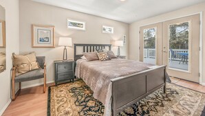 A bedroom with a bed, bedside tables, a rug, and a view of the outside. - Surf Song - Walk to the Beach (Lincoln City)