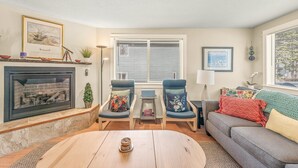 A living room with a fireplace, two armchairs, a sofa, and a coffee table. - Surf Song - Walk to the Beach (Lincoln City)
