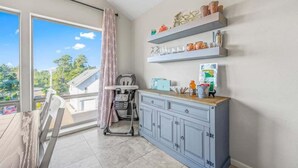 A room with a large sliding glass door leading to a balcony, a grey cabinet with shelves, and a stroller. - The Flip Flop Inn - Walk to the Beach (Lincoln City)