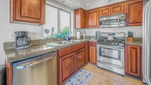 A kitchen with wooden cabinets, stainless steel appliances, granite countertops, and a dishwasher. - The Flip Flop Inn - Walk to the Beach (Lincoln City)