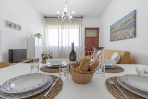 Ein Essbereich mit einem Tisch für vier Personen, komplett mit Weinglas, Brot und einem Gemälde an der Wand.