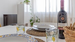 Een eettafel gedekt met borden, glazen en een fles wijn.