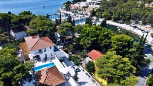 An aerial view of a coastal property with a swimming pool, a road, and a marina. - Exclusive Holiday Home Villa Marumare (Hvar)