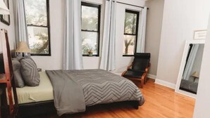 A bedroom with a bed, a chair, and a window. - Sun-Drenched Apartment in City Unit B (Baltimore)