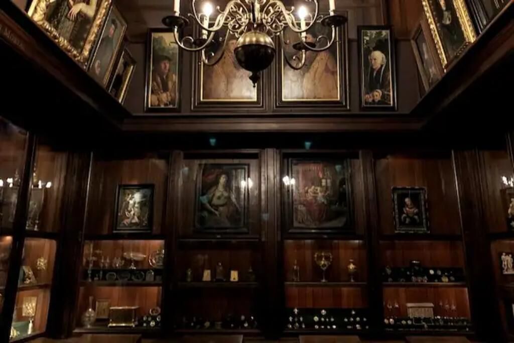 Um quarto com painéis de madeira, obras de arte emolduradas e um candelabro.