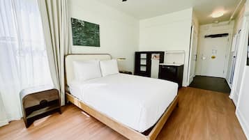A neatly arranged bedroom with a wooden bed, a ceiling fan, a small bedside table, and a wardrobe.