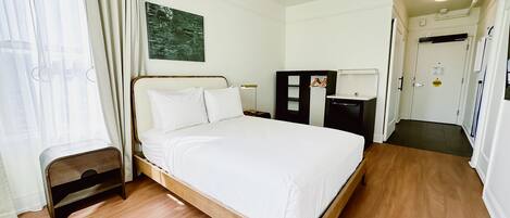 A neatly arranged bedroom with a wooden bed, a ceiling fan, a small bedside table, and a wardrobe.