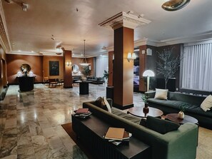 A spacious lobby with a marble floor, a reception desk, a sofa, and a coffee table.
