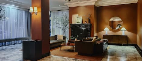 Eine großzügige Lobby mit Marmorboden, einer Couch, einem Couchtisch und einem Kamin.