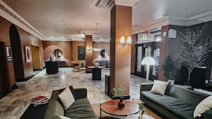A spacious lobby with a green sofa, a coffee table, and a reception desk. - FOUND Hotel Carlton, Nob Hill (San Francisco)