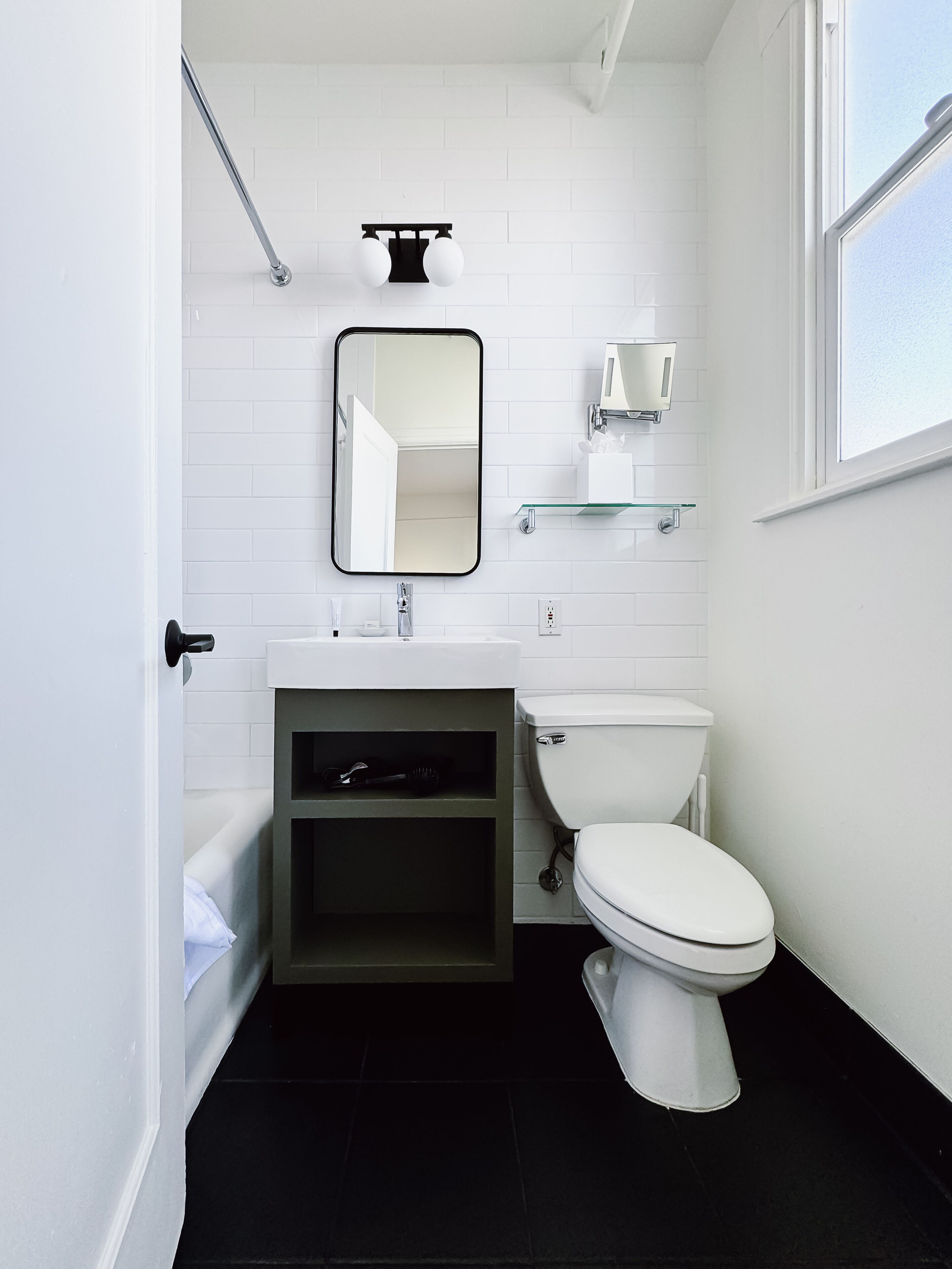 A modern bathroom with a white toilet, a glass shelf above the sink, and a mirror on the wall.
