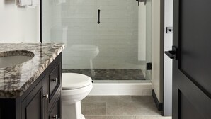 A modern bathroom with a glass-enclosed shower, a white toilet, and dark cabinetry. - FOUND Hotel Carlton, Nob Hill (San Francisco)