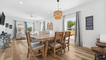 Un salon spacieux avec une table à manger en bois, des sièges confortables et une grande fenêtre donnant sur l’extérieur.