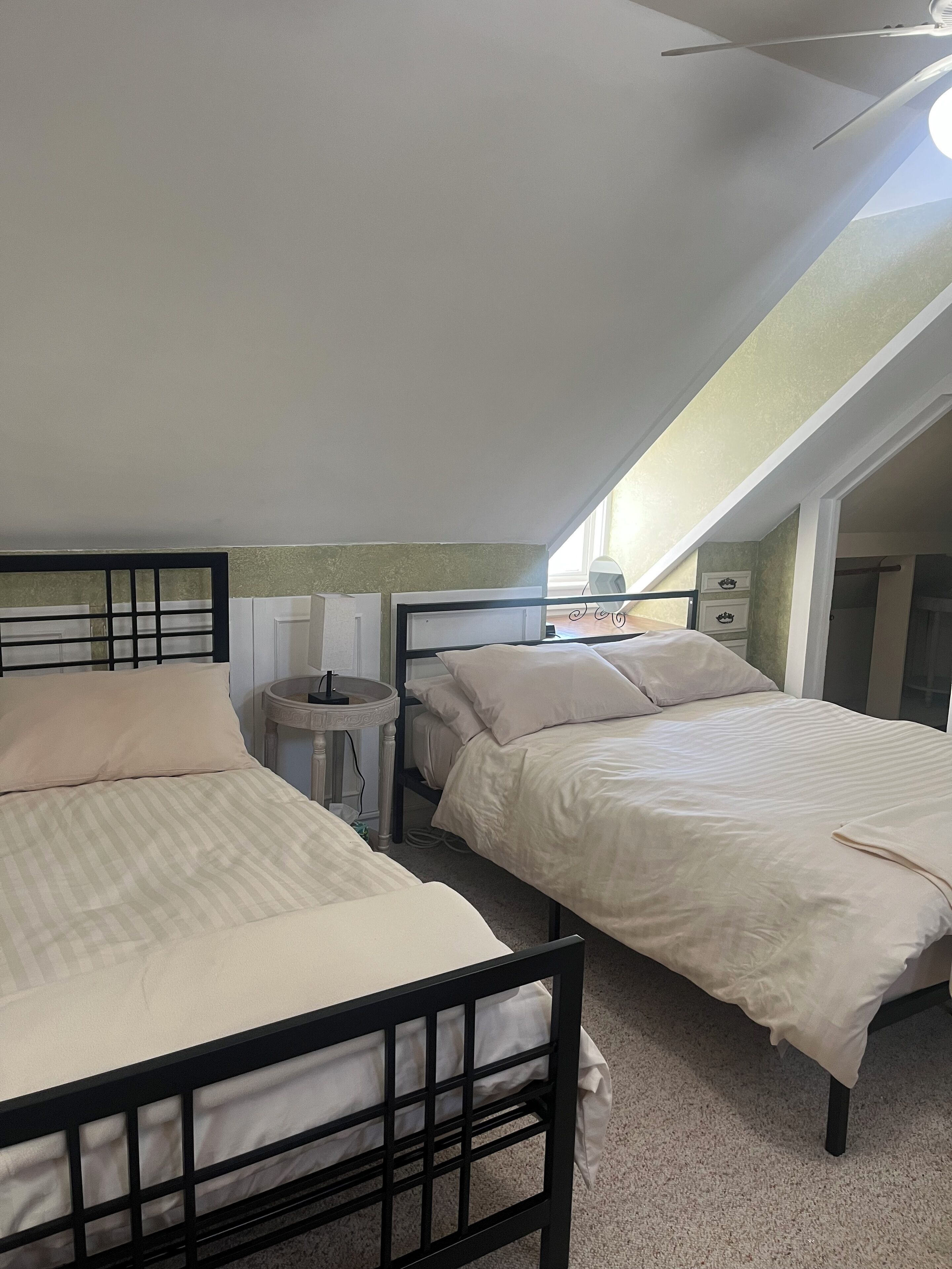 A room with two beds, a ceiling fan, and a skylight.