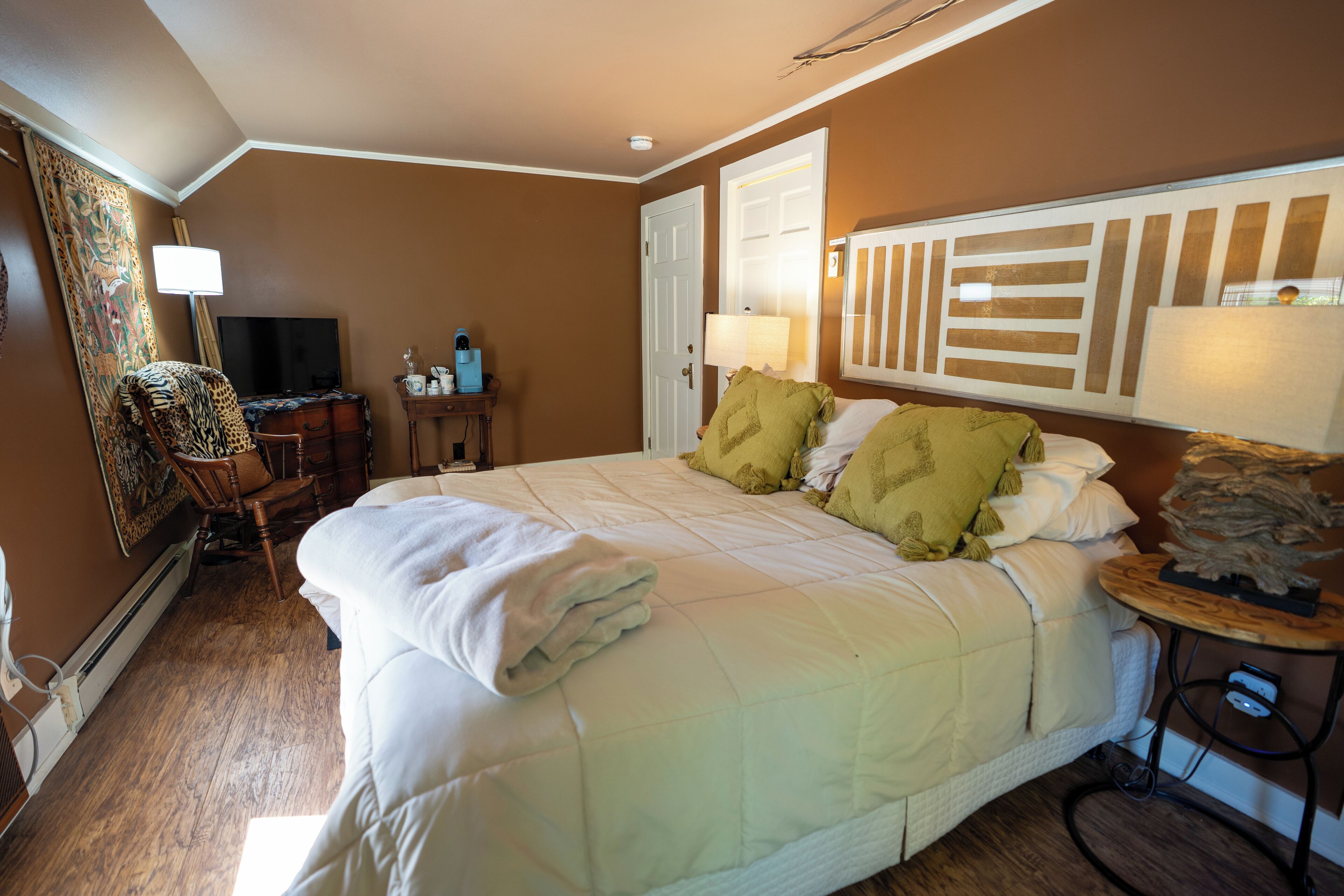 A hotel room with a large bed, a desk with a computer, a chair, and a television.