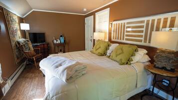 A hotel room with a large bed, a desk with a computer, a chair, and a television.