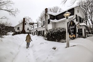 Un sendero cubierto de nieve que conduce a un edificio con un letrero que dice 'Admiral Peary Inn'.