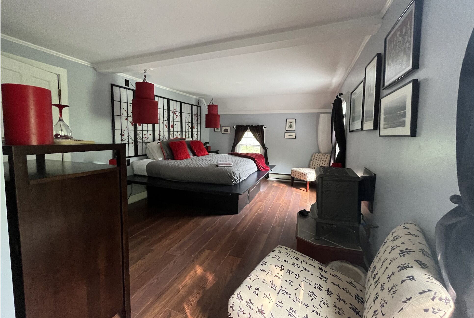 Un dormitorio con cama, una silla, un escritorio y un aparador.