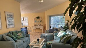 A living room with two sofas, a glass coffee table, and a large potted plant.