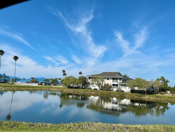 A two-story building with a balcony, surrounded by a body of water and palm trees.