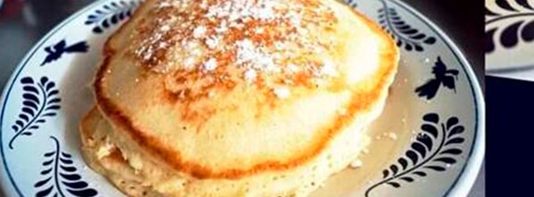A plate with a stack of pancakes topped with powdered sugar. - Hotel Yauco (Rosario)