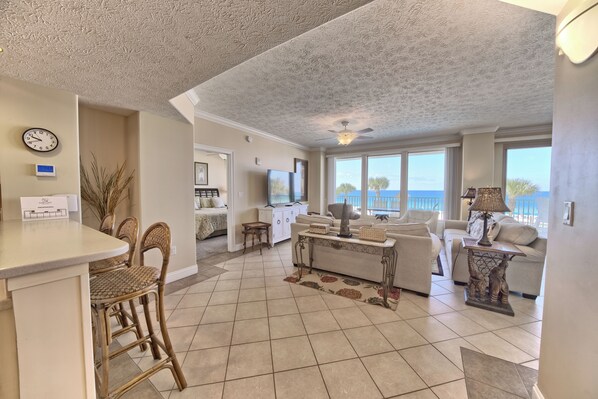 A spacious living area with a kitchen, dining area, and large windows offering a view of the ocean. - Beach Serenity: 2BR Coastal Haven w/ Beach Chairs (Panama City Beach)