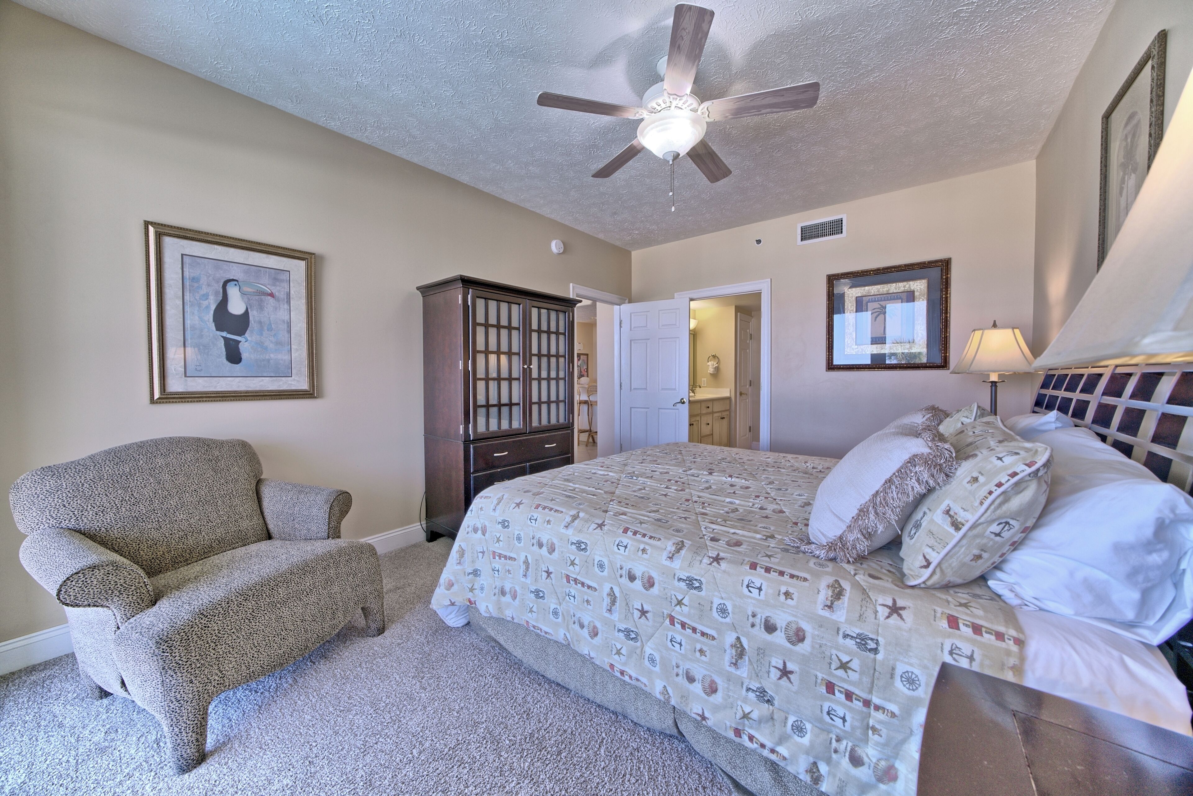 A bedroom with a bed, a chair, a ceiling fan, and a wardrobe.