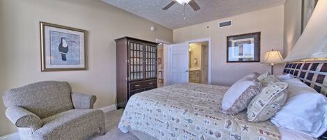 A bedroom with a bed, a chair, a ceiling fan, and a wardrobe.