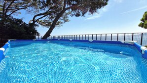 A clear blue swimming pool with a tiled edge, surrounded by a fence and trees. - Amazing View Costa Brava (Lloret de Mar)