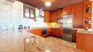 A kitchen with wooden cabinets, a stainless steel refrigerator, a microwave, and a stove. - Amazing View Costa Brava (Lloret de Mar)