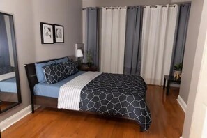 A bedroom with a bed, a nightstand, a lamp, and a mirror.