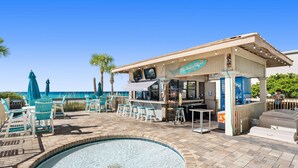 A poolside area with a bar, seating, and a view of the ocean.