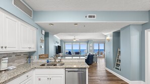 A spacious kitchen with a central island, white cabinetry, and a stainless steel dishwasher.
