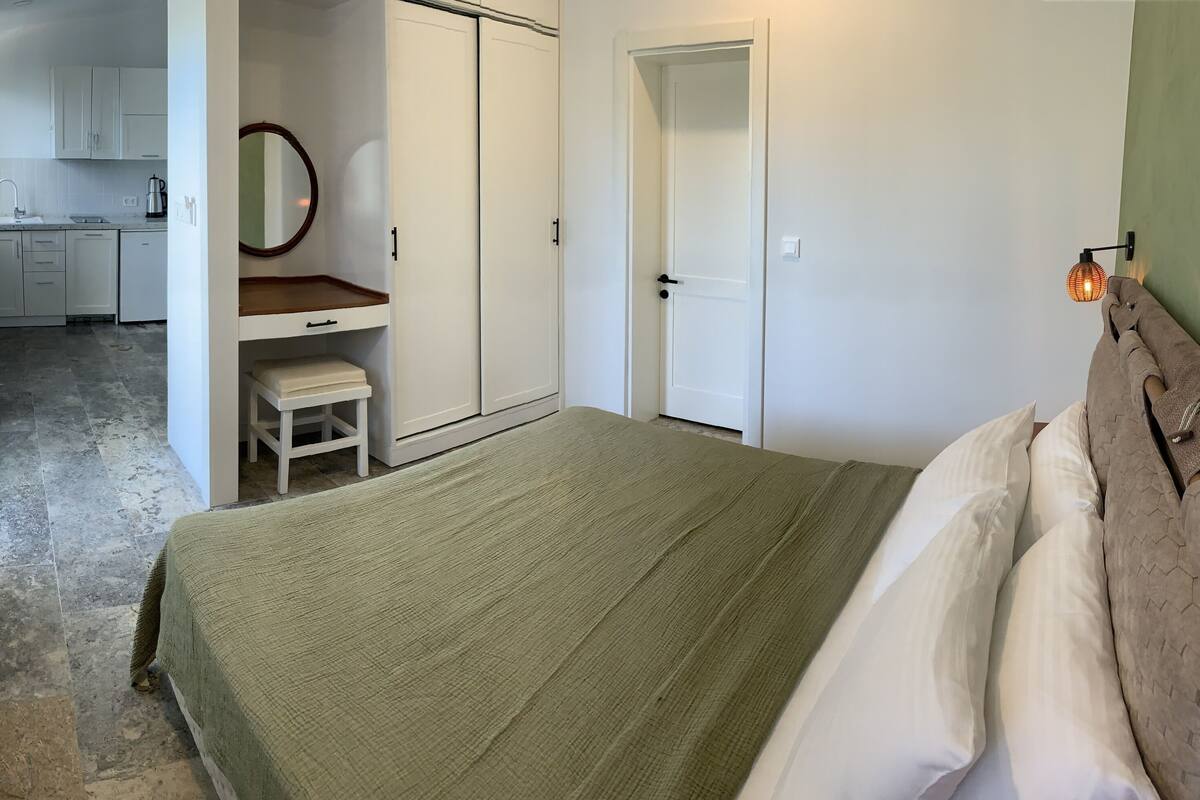 Une chambre à coucher comprenant un lit, une tête de lit en bois, une table de chevet et une armoire.