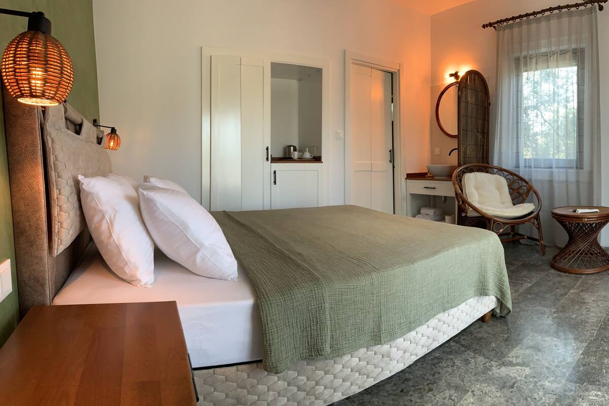 Une chambre à coucher comprenant un lit, une chaise, une petite table, un miroir et un téléviseur.
