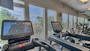 A gym with treadmills, an exercise bike, and a digital screen displaying workout metrics.