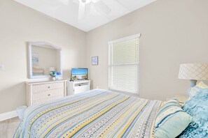 Un dormitorio con cama, cómoda, espejo y ventana con persianas.