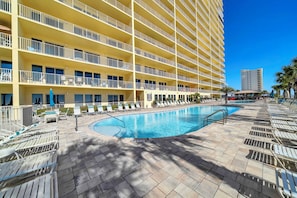 Un hotel con una piscina grande, varios balcones y tumbonas.