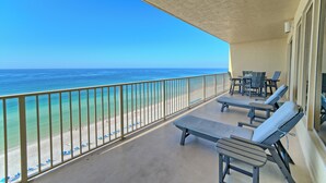 Ein Balkon mit Blick auf das Meer, Liegestühlen und einem Tisch.