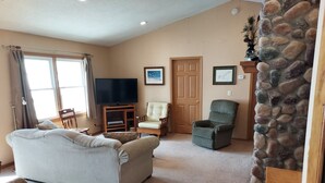 A living room with a sofa, a chair, a television, and a stone accent wall.