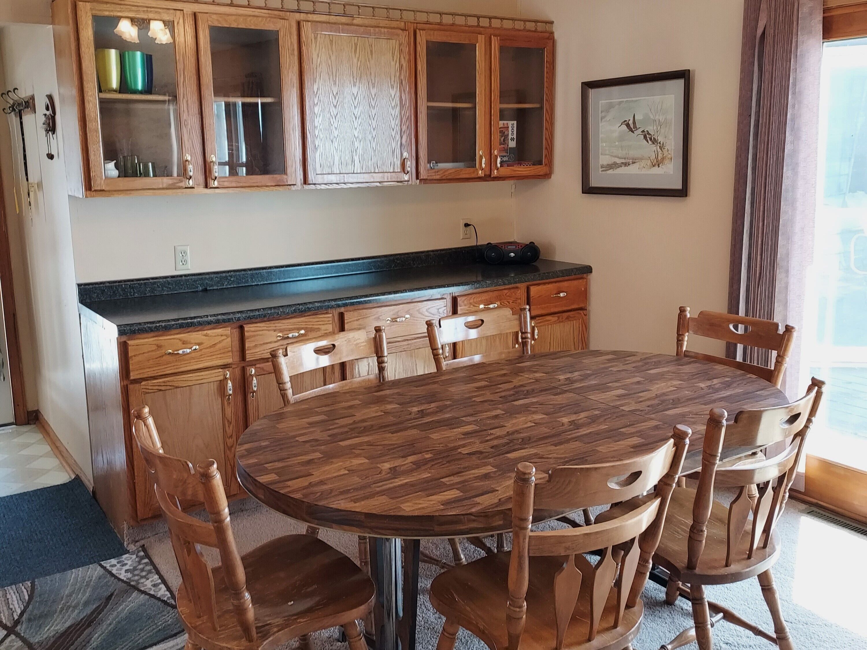 A kitchen with wooden cabinets, a round dining table, and chairs.
