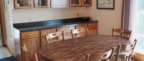 A kitchen with wooden cabinets, a round dining table, and chairs.
